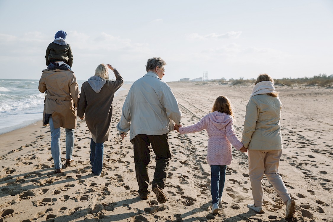 Multi-generational family on the beach holding hands